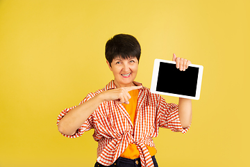 Image showing Senior woman isolated on yellow background. Tech and joyful elderly lifestyle concept