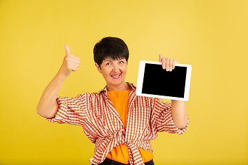 Image showing Senior woman isolated on yellow background. Tech and joyful elderly lifestyle concept