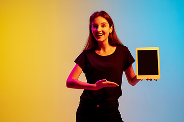 Image showing Young caucasian woman\'s portrait on gradient blue-yellow studio background in neon light