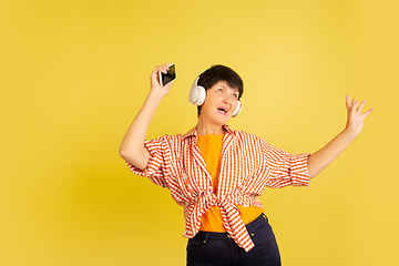 Image showing Senior woman isolated on yellow background. Tech and joyful elderly lifestyle concept