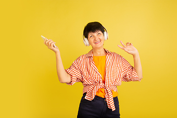 Image showing Senior woman isolated on yellow background. Tech and joyful elderly lifestyle concept