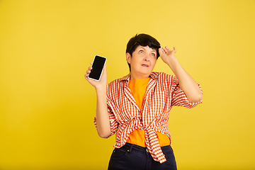 Image showing Senior woman isolated on yellow background. Tech and joyful elderly lifestyle concept