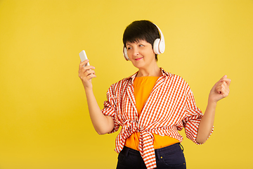 Image showing Senior woman isolated on yellow background. Tech and joyful elderly lifestyle concept