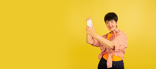 Image showing Senior woman isolated on yellow background. Tech and joyful elderly lifestyle concept