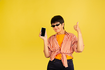 Image showing Senior woman isolated on yellow background. Tech and joyful elderly lifestyle concept