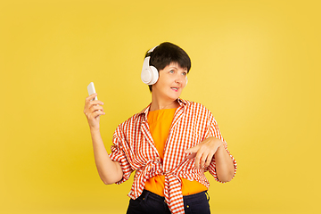 Image showing Senior woman isolated on yellow background. Tech and joyful elderly lifestyle concept