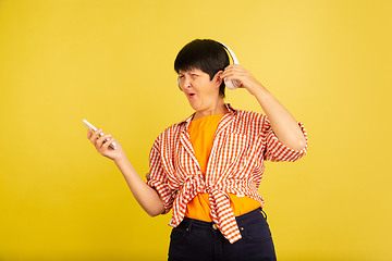 Image showing Senior woman isolated on yellow background. Tech and joyful elderly lifestyle concept