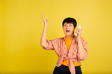 Image showing Senior woman isolated on yellow background. Tech and joyful elderly lifestyle concept