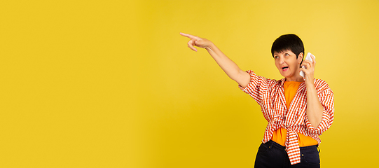 Image showing Senior woman isolated on yellow background. Tech and joyful elderly lifestyle concept