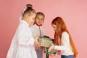 Image showing Giving and getting presents on Christmas holidays. Group of happy smiling children having fun isolated on pink studio background