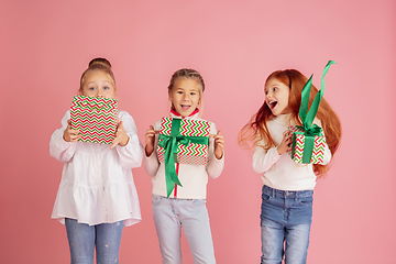 Image showing Giving and getting presents on Christmas holidays. Group of happy smiling children having fun isolated on pink studio background