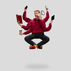 Image showing Handsome multi-armed student levitating isolated on grey studio background with equipment