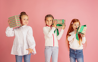 Image showing Giving and getting presents on Christmas holidays. Group of happy smiling children having fun isolated on pink studio background