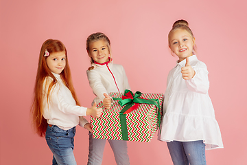 Image showing Giving and getting presents on Christmas holidays. Group of happy smiling children having fun isolated on pink studio background