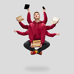 Image showing Handsome multi-armed student levitating isolated on grey studio background with equipment