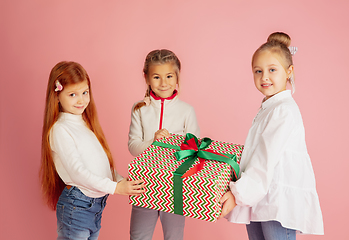 Image showing Giving and getting presents on Christmas holidays. Group of happy smiling children having fun isolated on pink studio background