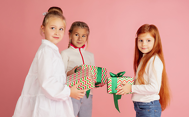 Image showing Giving and getting presents on Christmas holidays. Group of happy smiling children having fun isolated on pink studio background