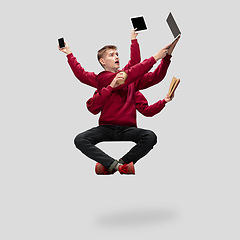 Image showing Handsome multi-armed student levitating isolated on grey studio background with equipment