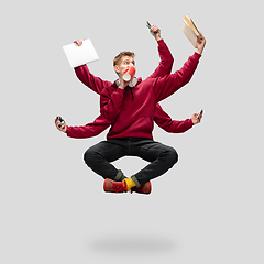 Image showing Handsome multi-armed student levitating isolated on grey studio background with equipment