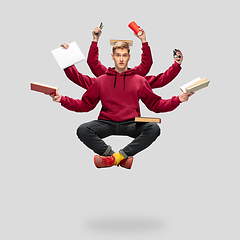 Image showing Handsome multi-armed student levitating isolated on grey studio background with equipment