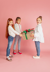 Image showing Giving and getting presents on Christmas holidays. Group of happy smiling children having fun isolated on pink studio background