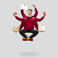 Image showing Handsome multi-armed student levitating isolated on grey studio background with equipment