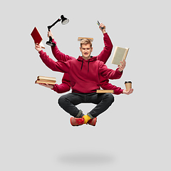 Image showing Handsome multi-armed student levitating isolated on grey studio background with equipment