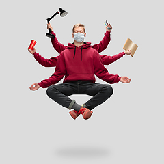 Image showing Handsome multi-armed student levitating isolated on grey studio background with equipment