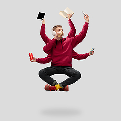 Image showing Handsome multi-armed student levitating isolated on grey studio background with equipment