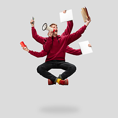 Image showing Handsome multi-armed student levitating isolated on grey studio background with equipment