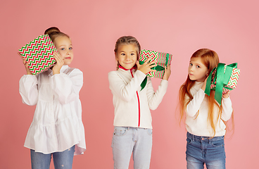 Image showing Giving and getting presents on Christmas holidays. Group of happy smiling children having fun isolated on pink studio background