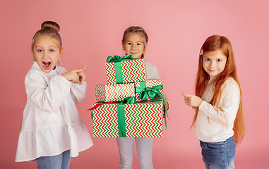 Image showing Giving and getting presents on Christmas holidays. Group of happy smiling children having fun isolated on pink studio background