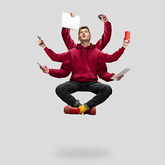 Image showing Handsome multi-armed student levitating isolated on grey studio background with equipment