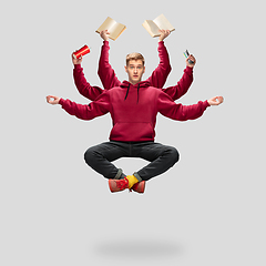 Image showing Handsome multi-armed student levitating isolated on grey studio background with equipment