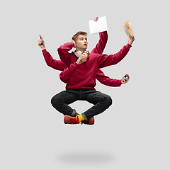 Image showing Handsome multi-armed student levitating isolated on grey studio background with equipment