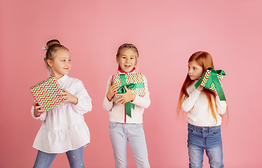 Image showing Giving and getting presents on Christmas holidays. Group of happy smiling children having fun isolated on pink studio background