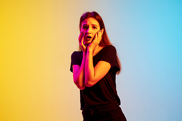 Image showing Young caucasian woman\'s portrait on gradient blue-yellow studio background in neon light