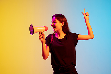 Image showing Young caucasian woman\'s portrait on gradient blue-yellow studio background in neon light