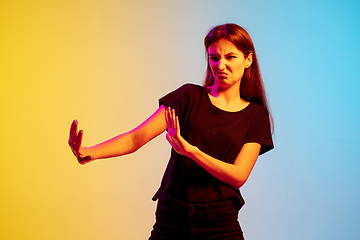 Image showing Young caucasian woman\'s portrait on gradient blue-yellow studio background in neon light