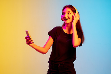 Image showing Young caucasian woman\'s portrait on gradient blue-yellow studio background in neon light