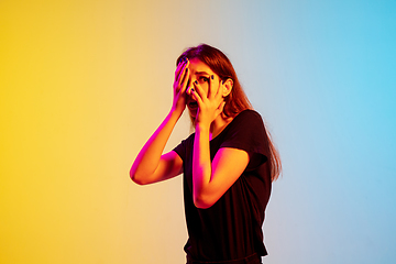 Image showing Young caucasian woman\'s portrait on gradient blue-yellow studio background in neon light