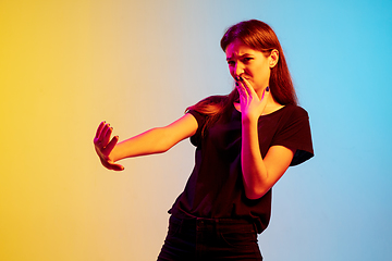 Image showing Young caucasian woman\'s portrait on gradient blue-yellow studio background in neon light