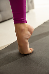 Image showing Close up of beautiful young woman working out indoors, doing yoga exercise on gray mat, details