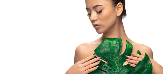 Image showing Close up young woman\'s portrait with monstera leaf on white background. Cosmetics and makeup, natural and eco treatment, skin care.