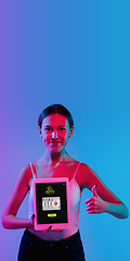 Image showing Online gambling, casino concept. Young woman holding devices with lottery, casino cover in neon light