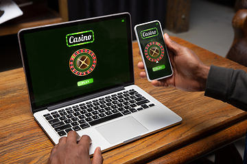 Image showing Online gambling, casino concept. Hand near laptop, device with lottery, casino cover