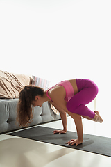 Image showing Beautiful young woman working out indoors, doing yoga exercise on gray mat at home