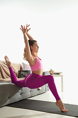 Image showing Beautiful young woman working out indoors, doing yoga exercise on gray mat at home