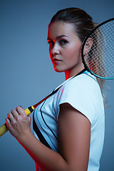 Image showing Beautiful handicap woman practicing in badminton isolated on blue background in neon light