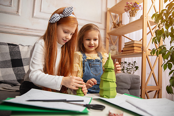 Image showing Two little children, girls together in creativity of the house. Happy kids make handmade toys for games or New Year celebration